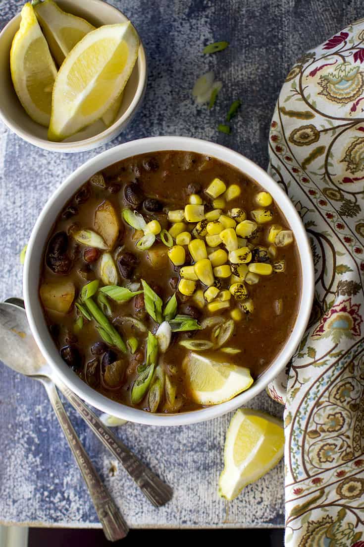 Bowl of Black bean veggie soup with lemon wedges