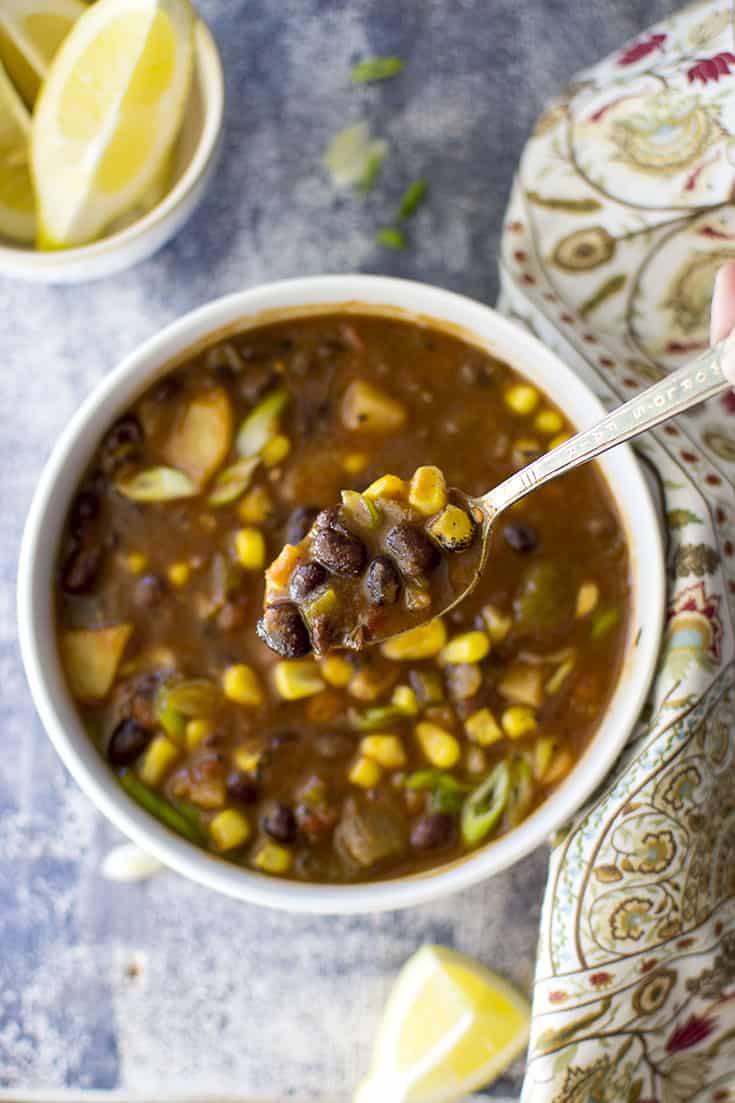 Spoon and bowl with black bean soup with vegetables