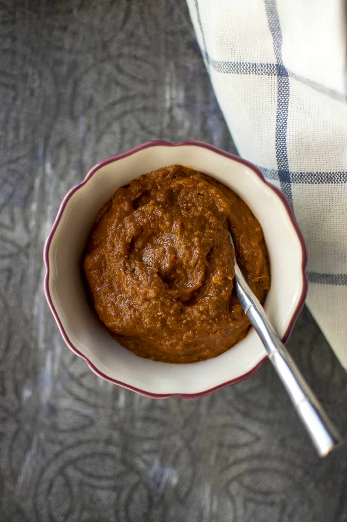 Cream bowl with ginger chutney & steel spoon inside.