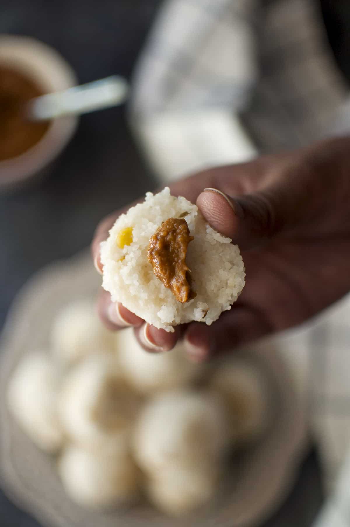 Hand holding half kudumu topped with ginger chutney.