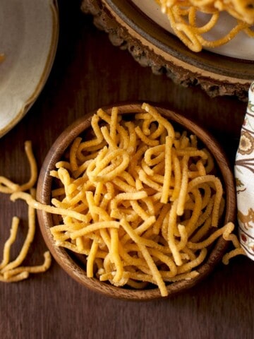 Top view of a wooden bowl filled with besan murukku