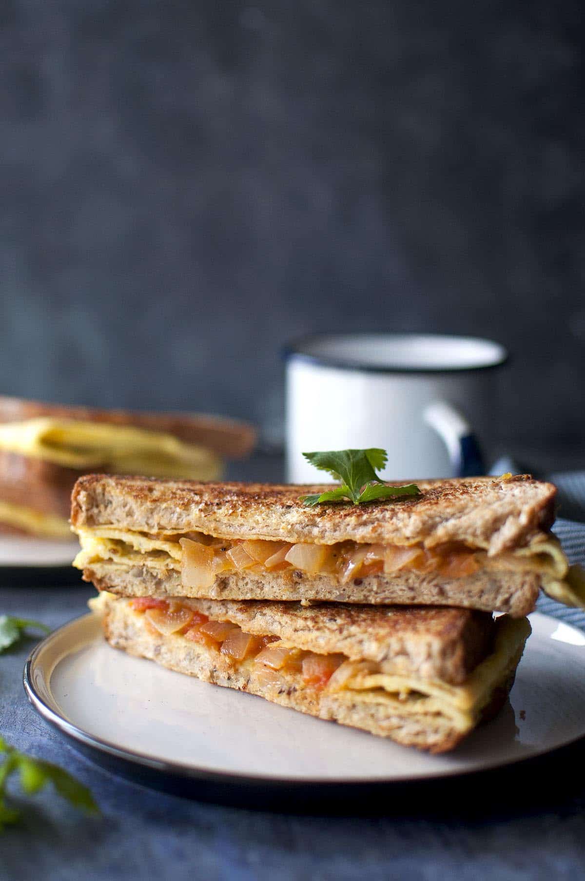 White plate with bread omelette sandwich halves stacked on each other