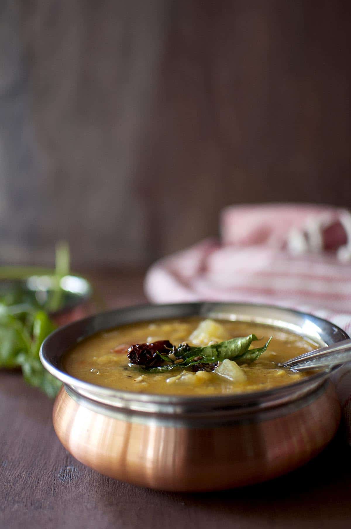 copper bottom bowl with Andhra cucumber dal with a spoon inside