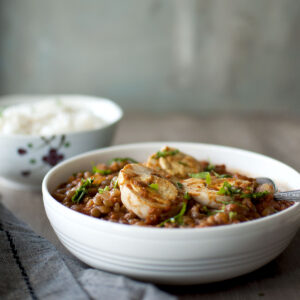 White bowl with boiled egg curry with lentils.