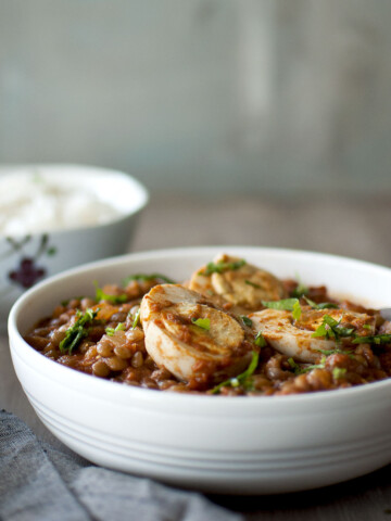 White bowl with boiled egg curry with lentils.