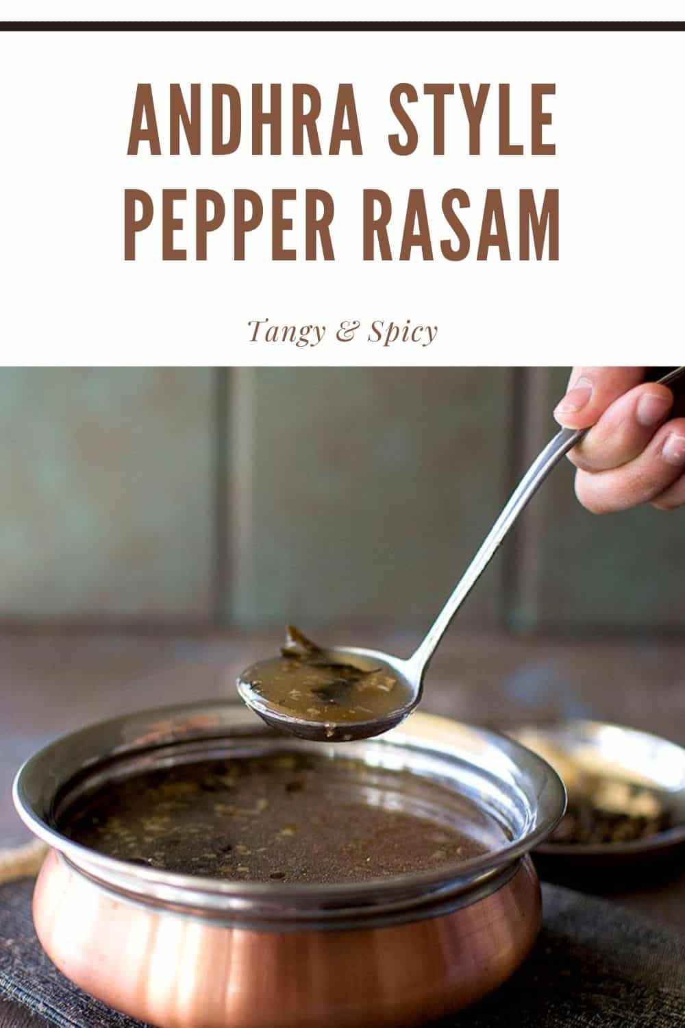 Hand holding a spoon over a bowl of pepper rasam.