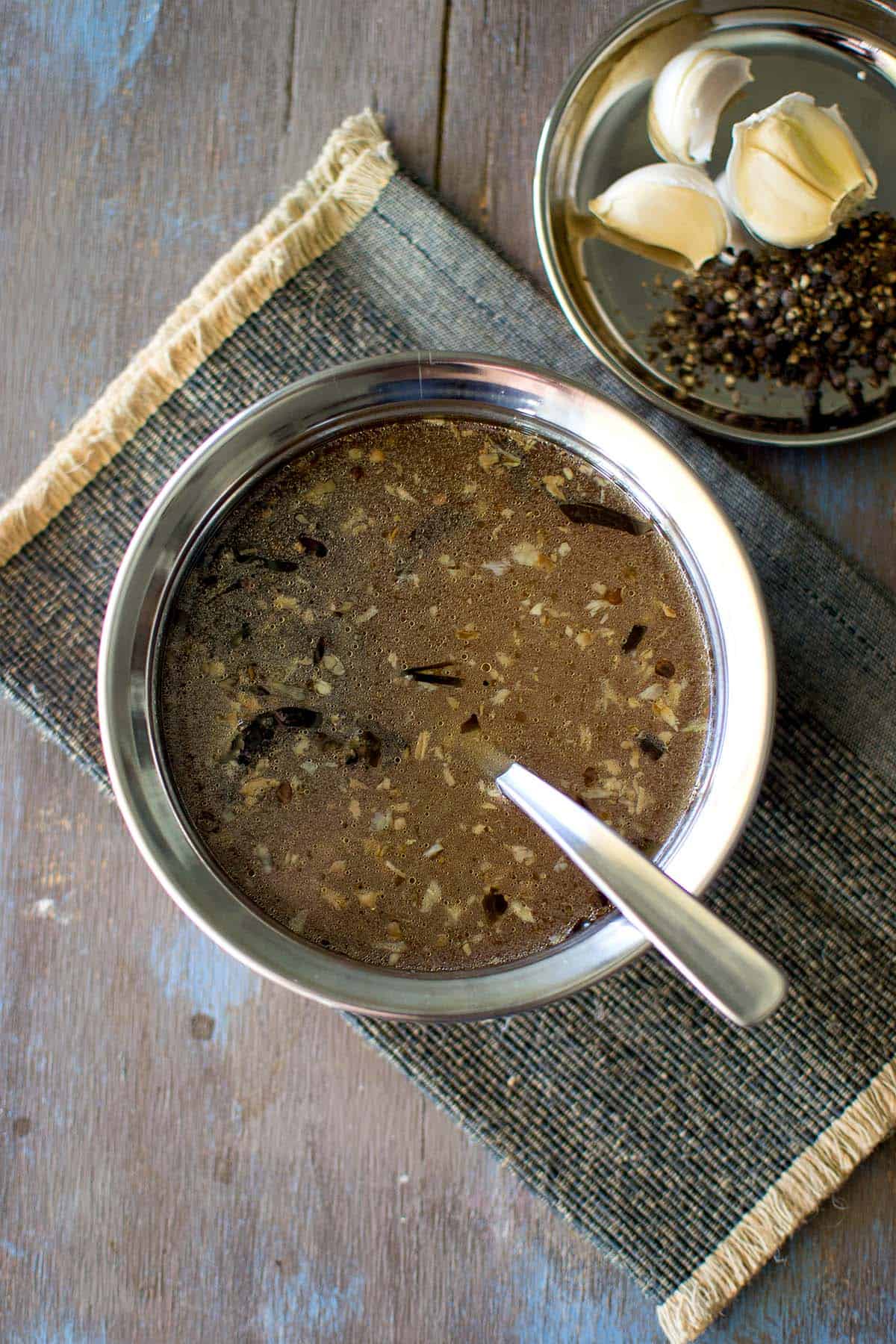 Steel bowl with Miriyala charu and a spoon.