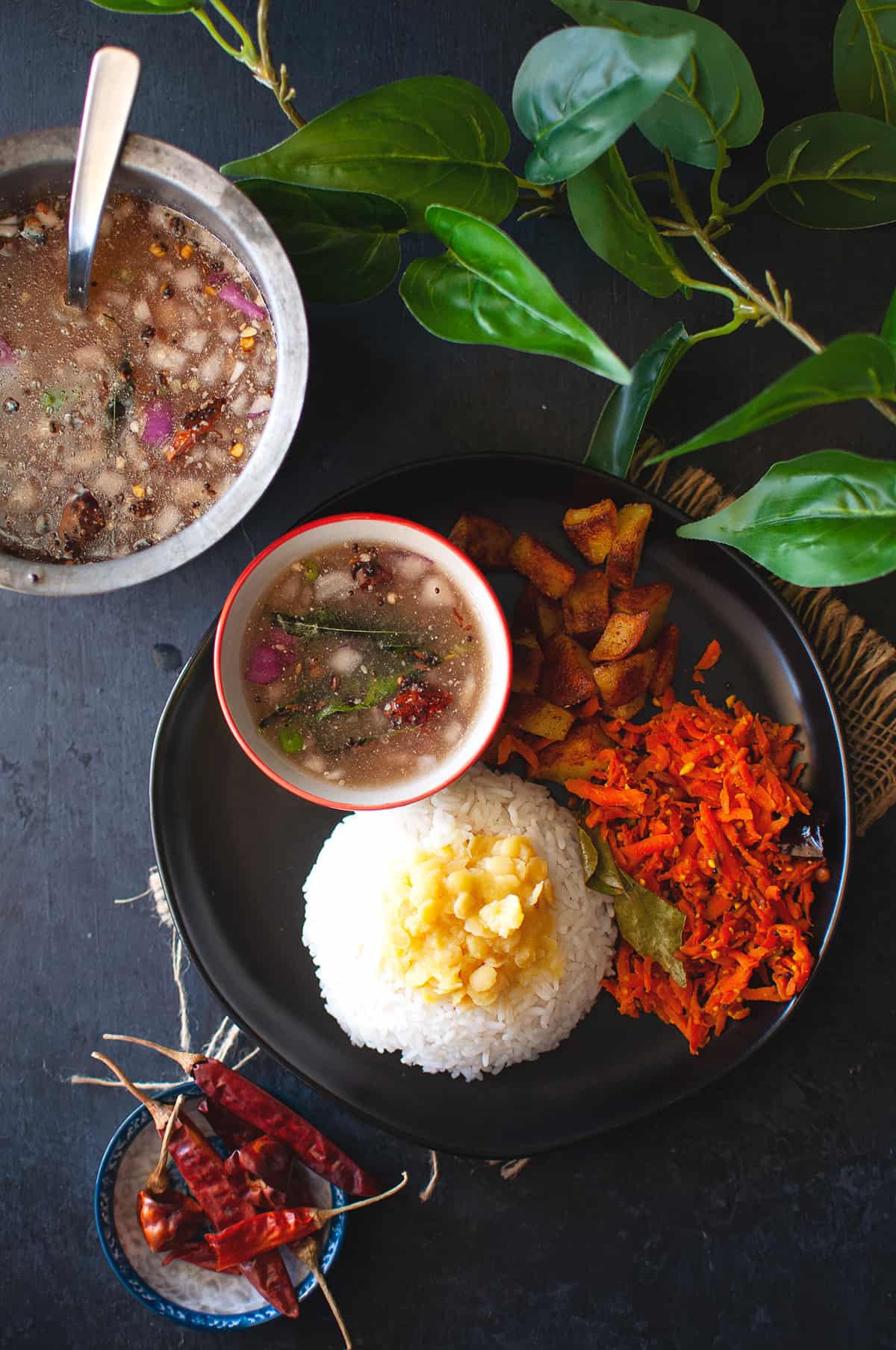 Black plate with rice, dal, carrot curry and stew.