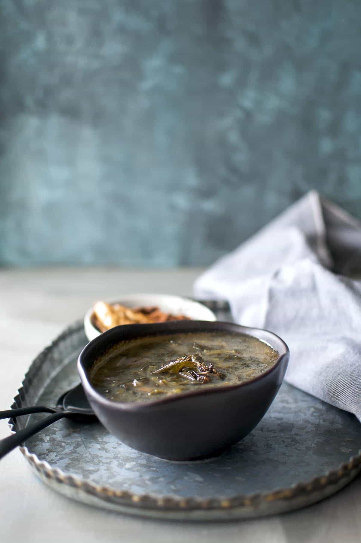 pewter tray with black bowl with spinach soup