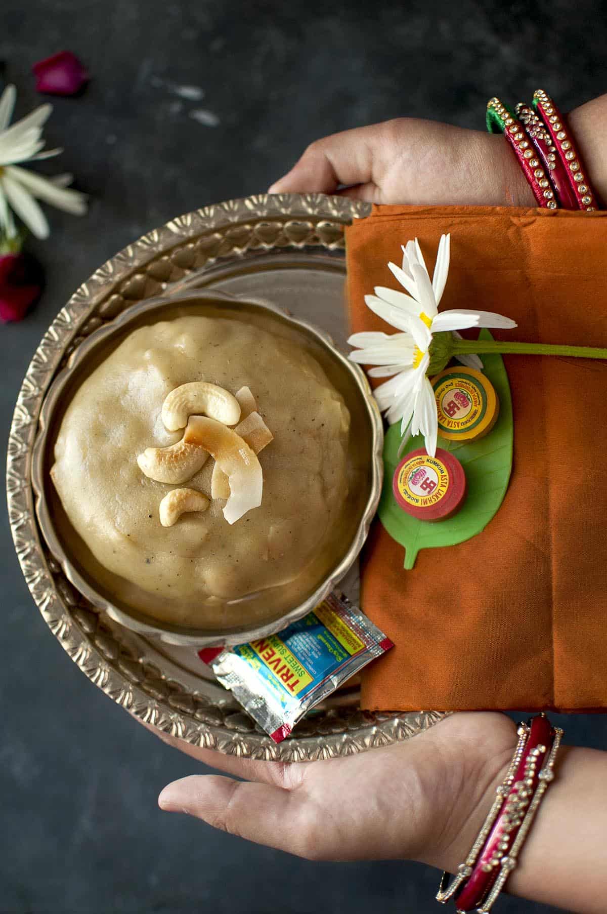 Hand holding a plate with chalimidi and a flower