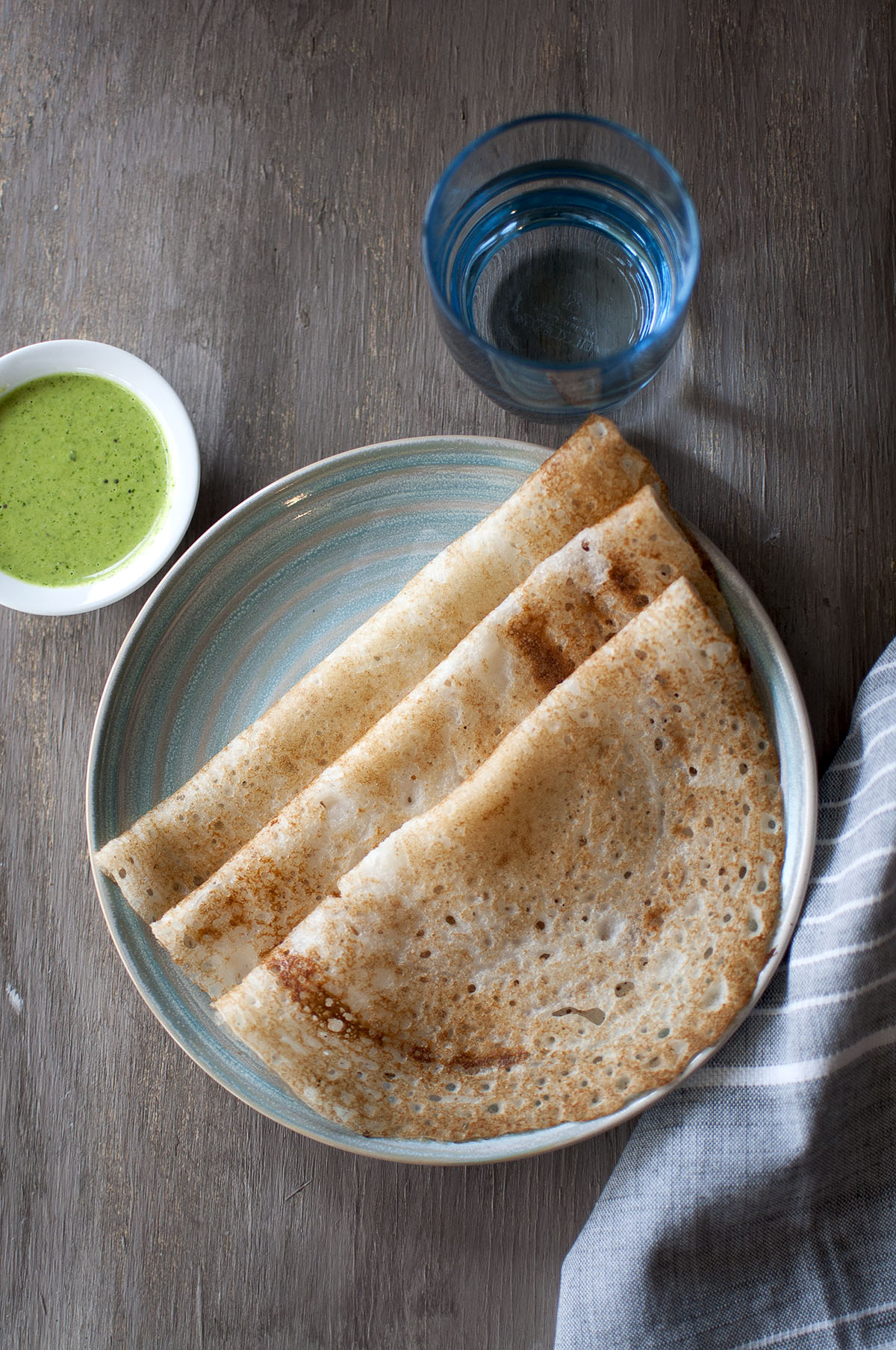 Blue plate with poha dosa and a bowl with green chutney