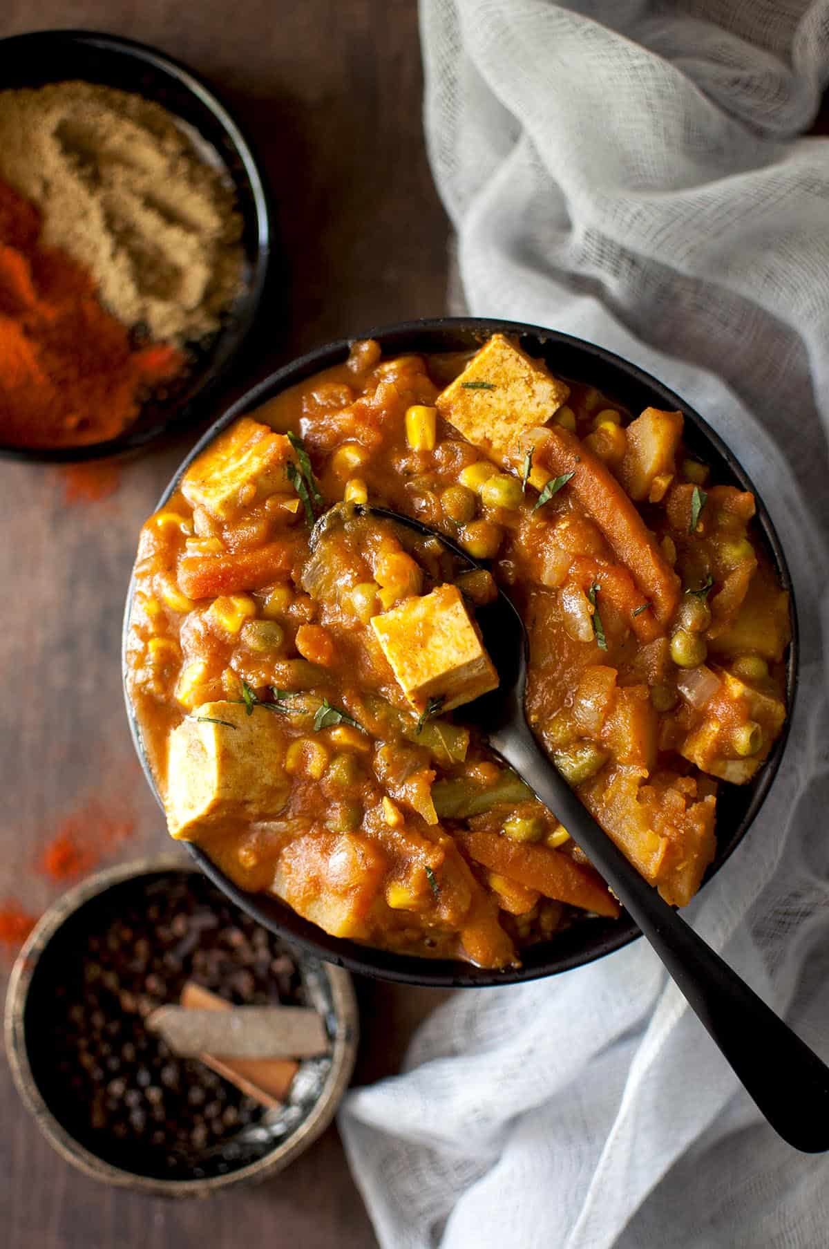 Black spoon on a bowl of vegetarian vindaloo