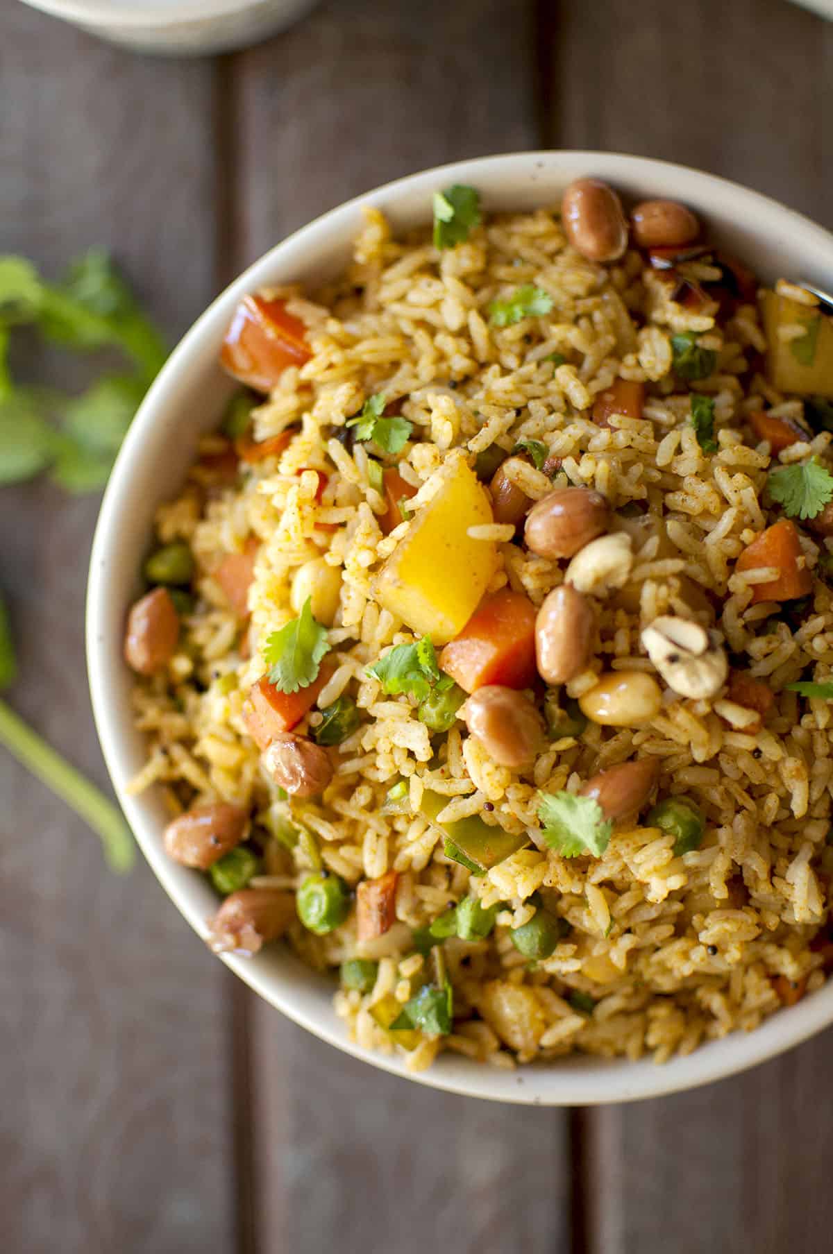 White bowl with colorful vegetable rice topped with peanuts and cashews