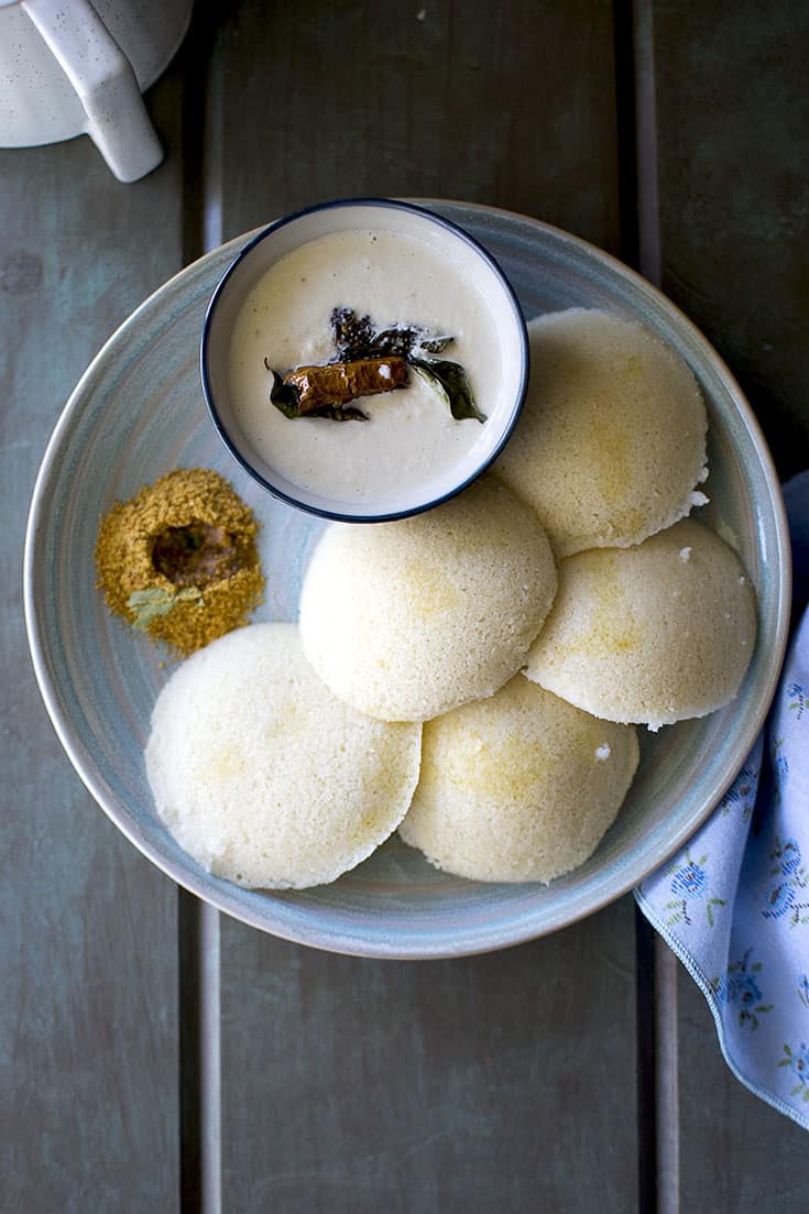 Blue plate with 5 idli with podi and coconut chutney