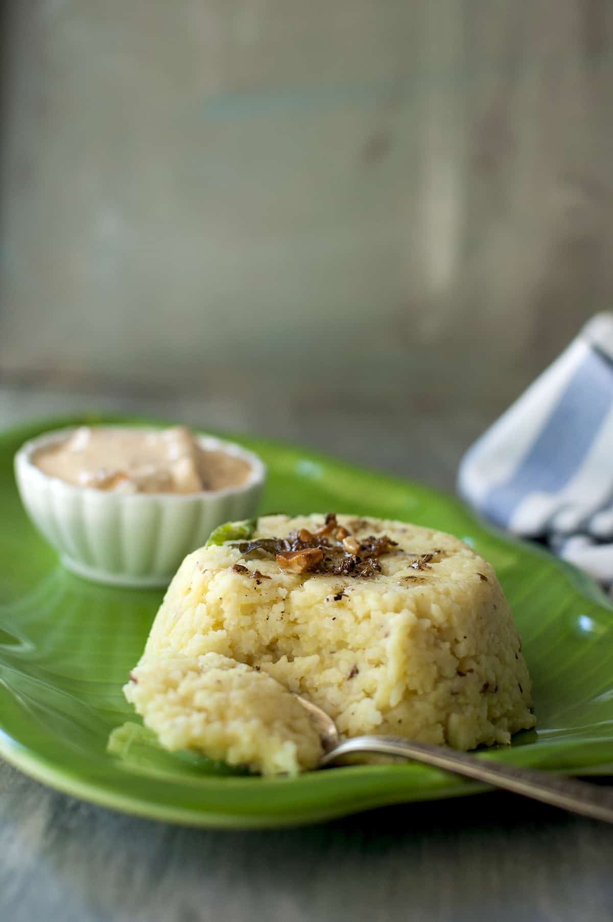 green plate with a spoon of scooped up pongal