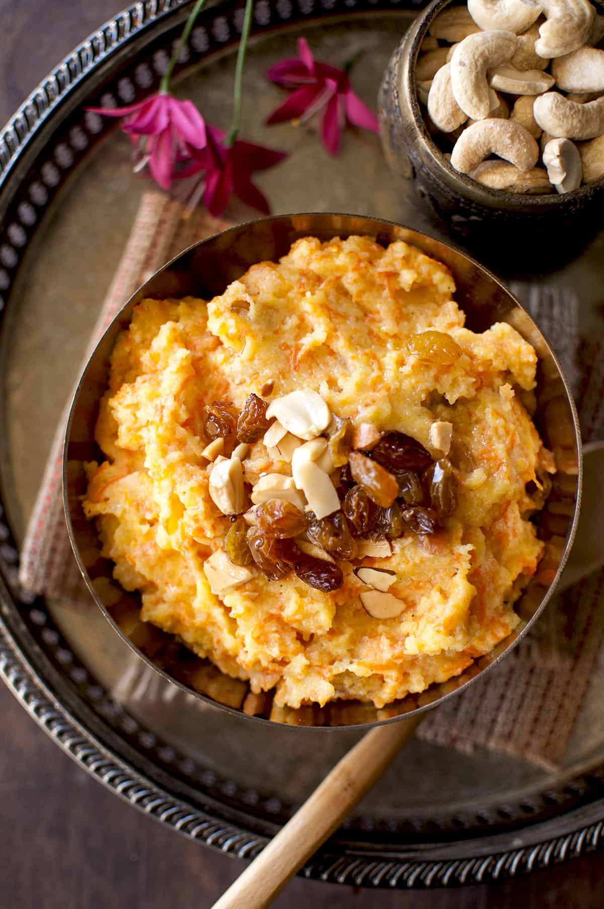 Brass bowl with shahi halwa with carrots topped with raisins and nuts