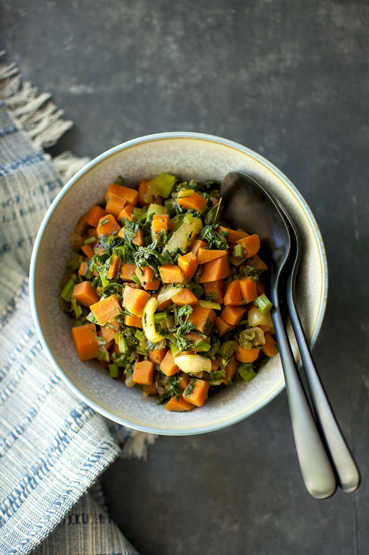 Top view of a bowl with greens and carrot stir fry.
