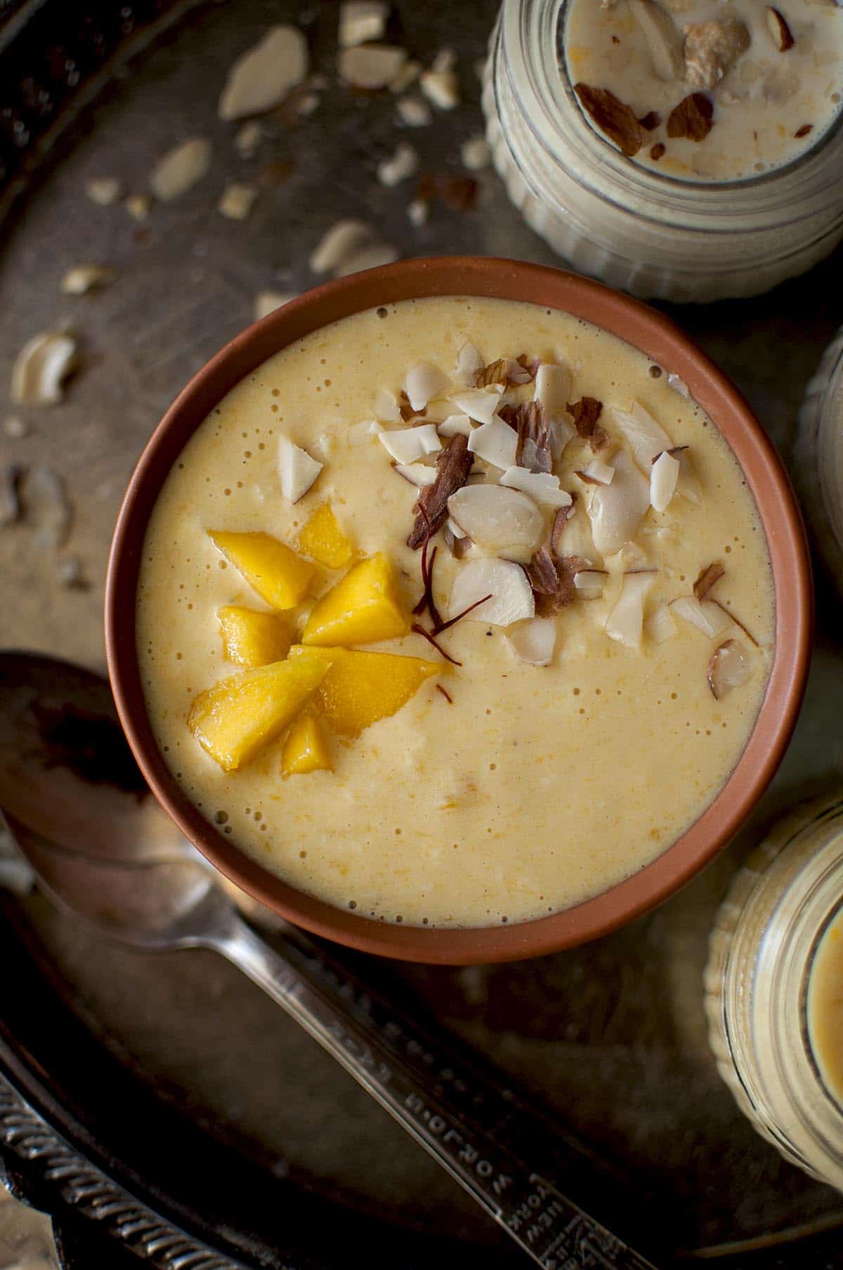 Terracotta bowl with aam kheer topped with diced mango and chopped nuts