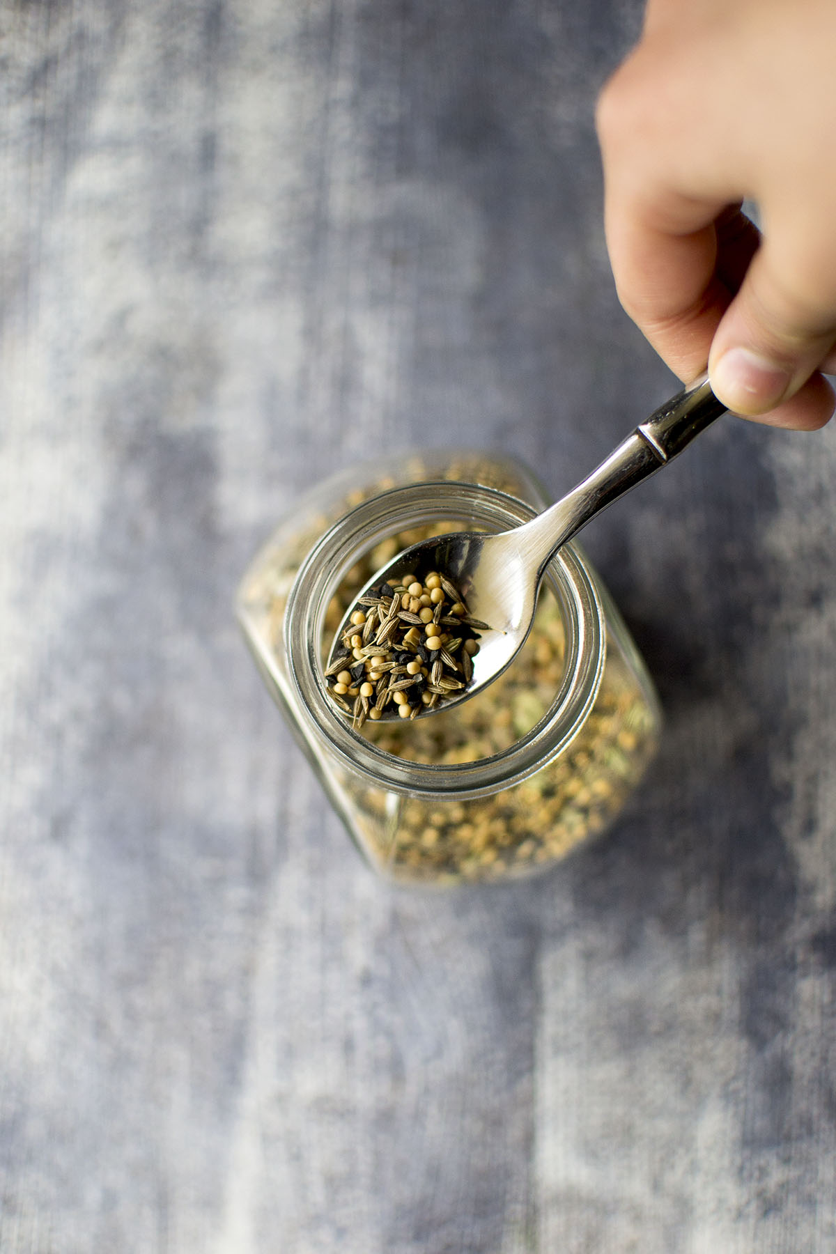 Hand holding a spoon with spice blend.