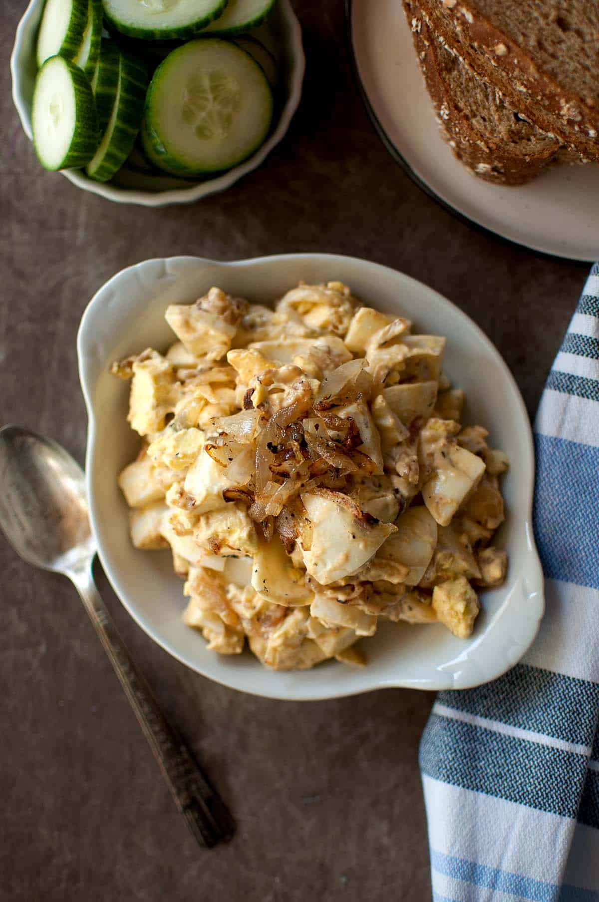 White bowl with egg salad with caramelized onions.