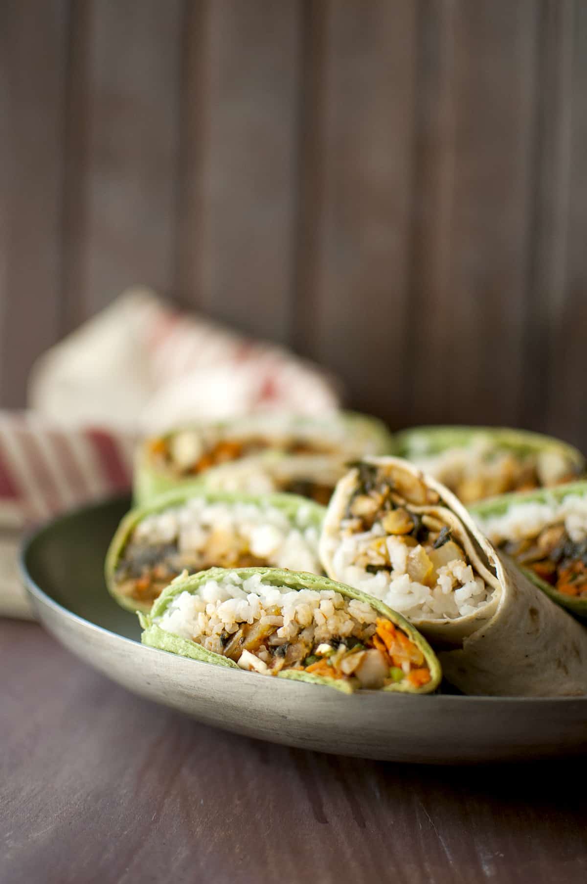 Steel plate with rice and veggie stuffed wrap sandwiches.