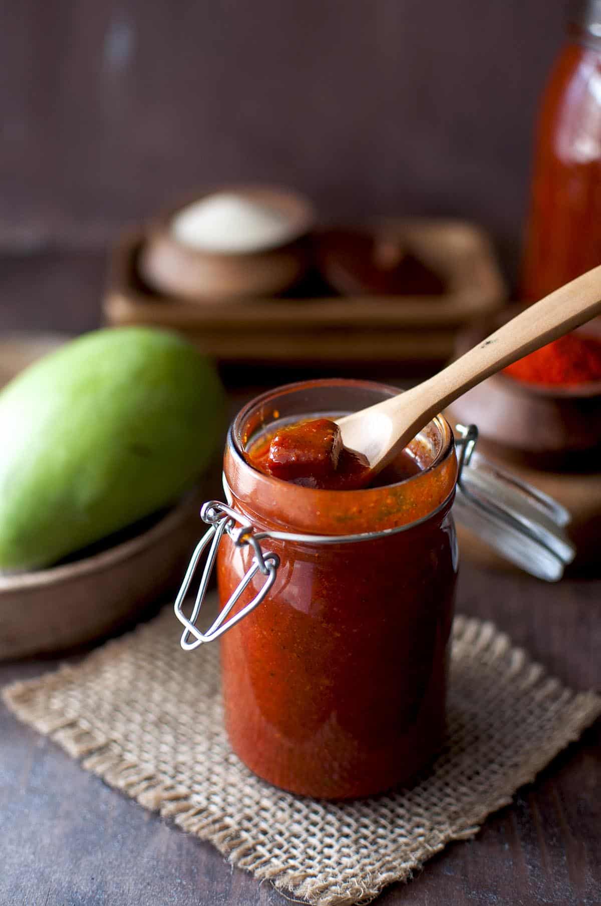 Glass bottle with teepi avakaya with a wooden spoon in it