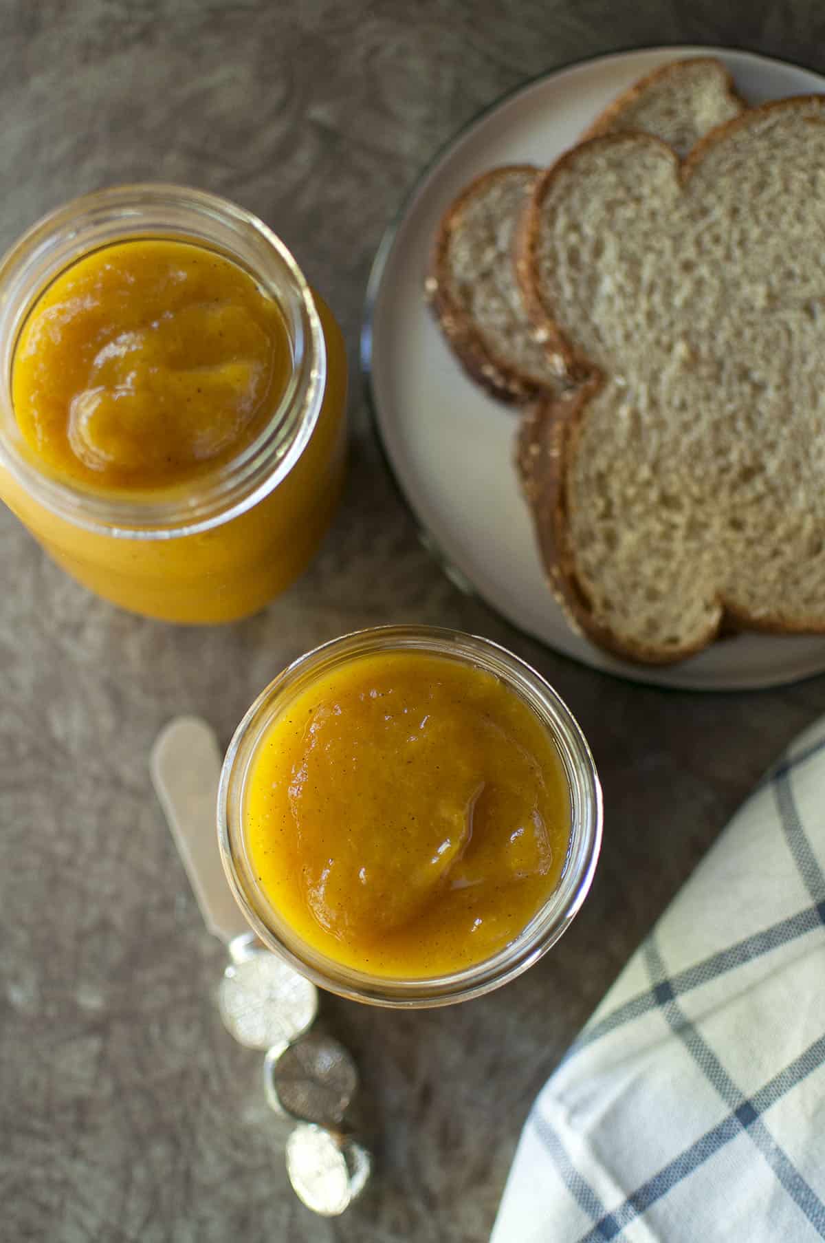 Glass jar with jelly and bread in the background