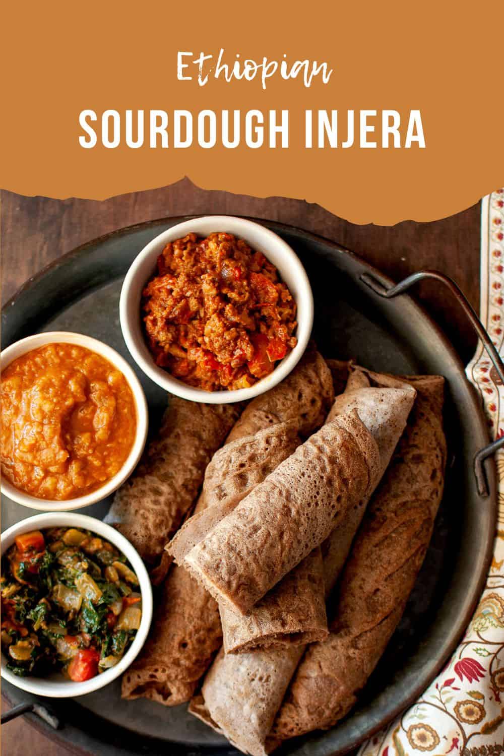 Tray with rolled Sourdough Injera and bowls of side dishes.