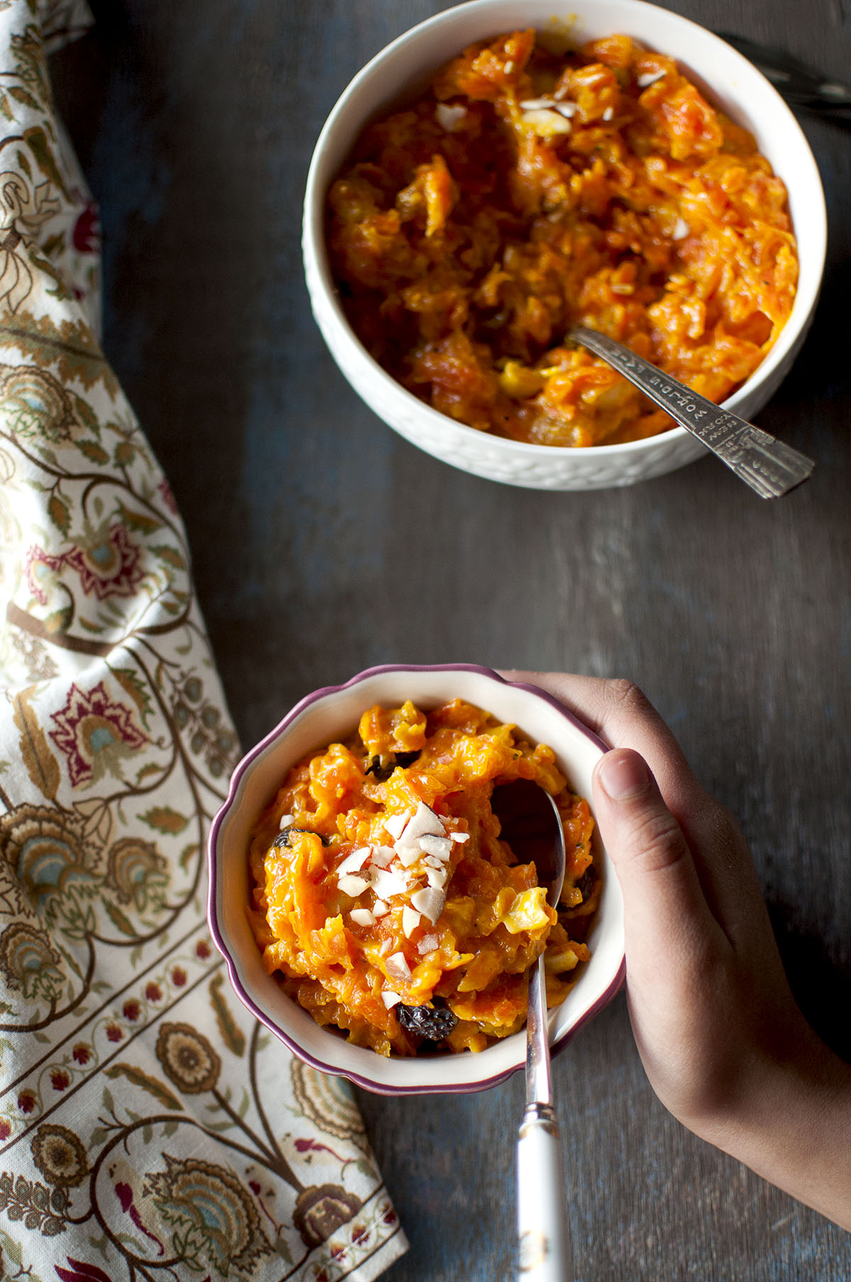 Hand holding a bowl of carrot dessert with spoon