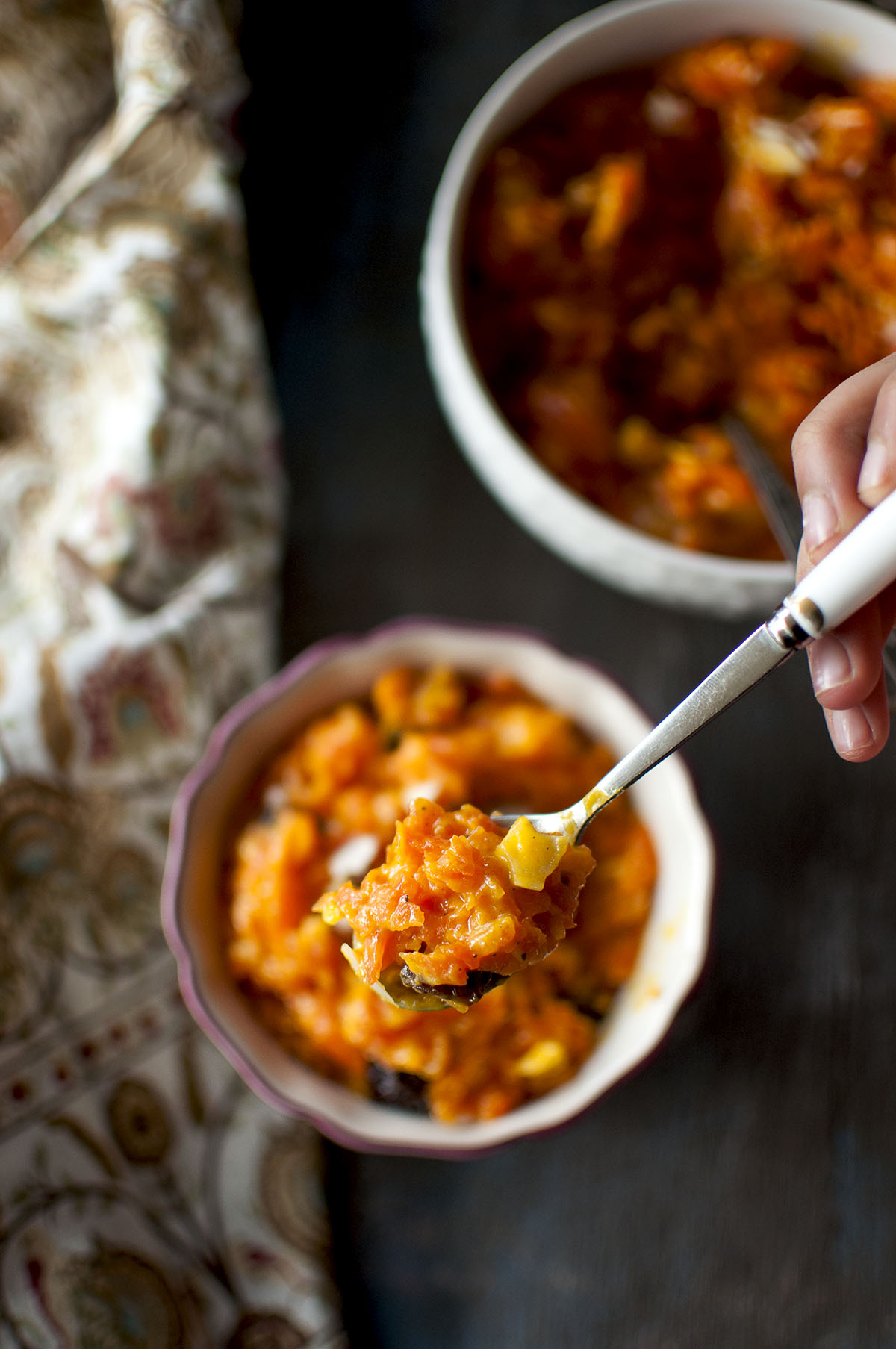 Hand holding a spoon with carrot halwa