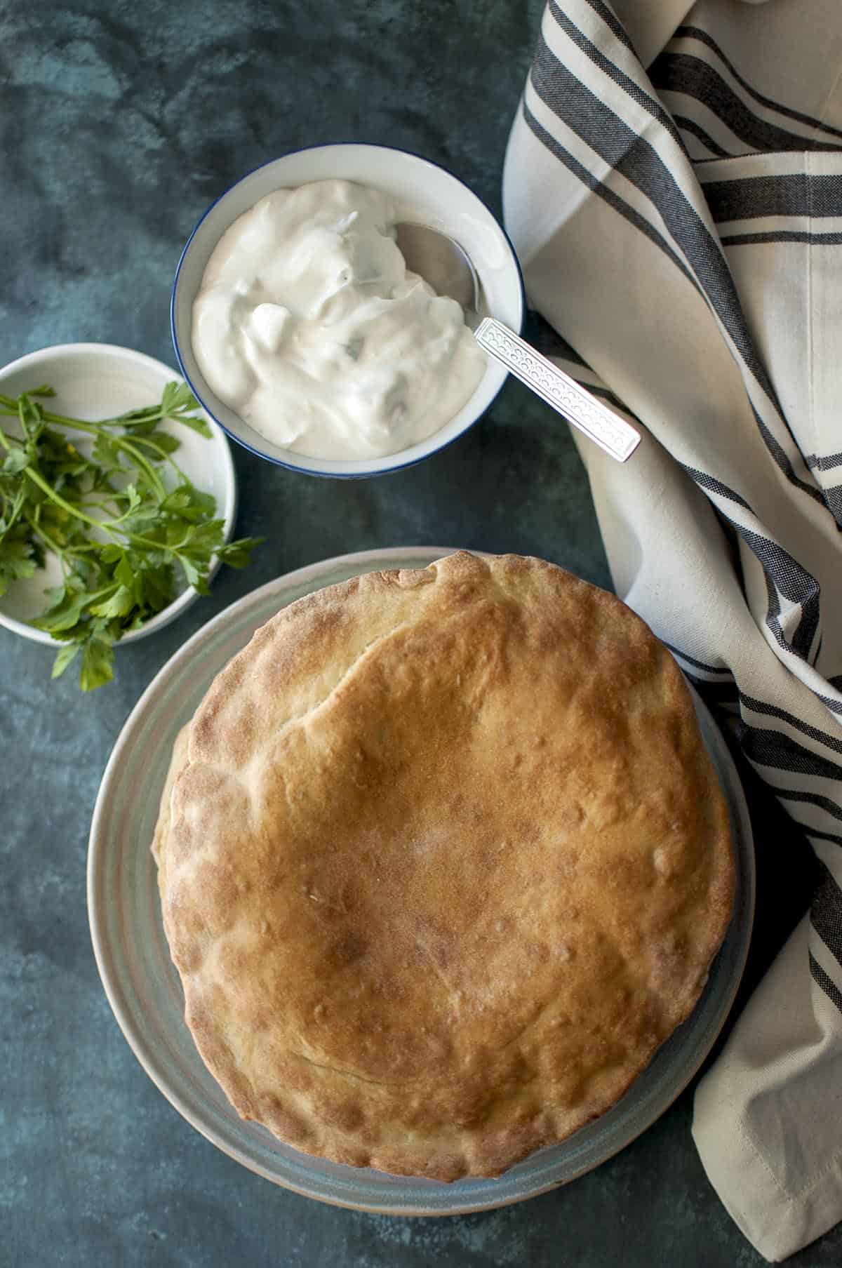 Grey plate with Sourdough Onion kulcha with yogurt in a bowl