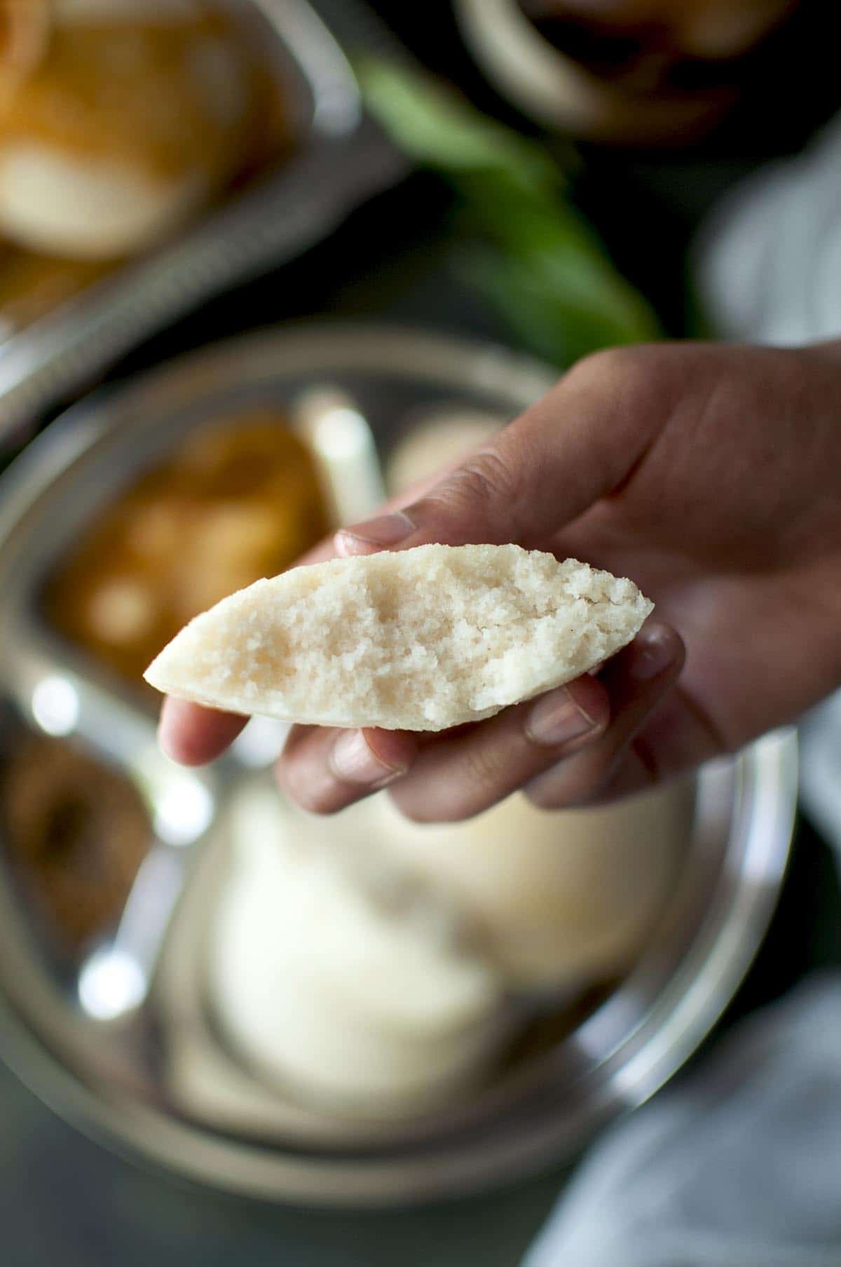 Hand holding half a Idli