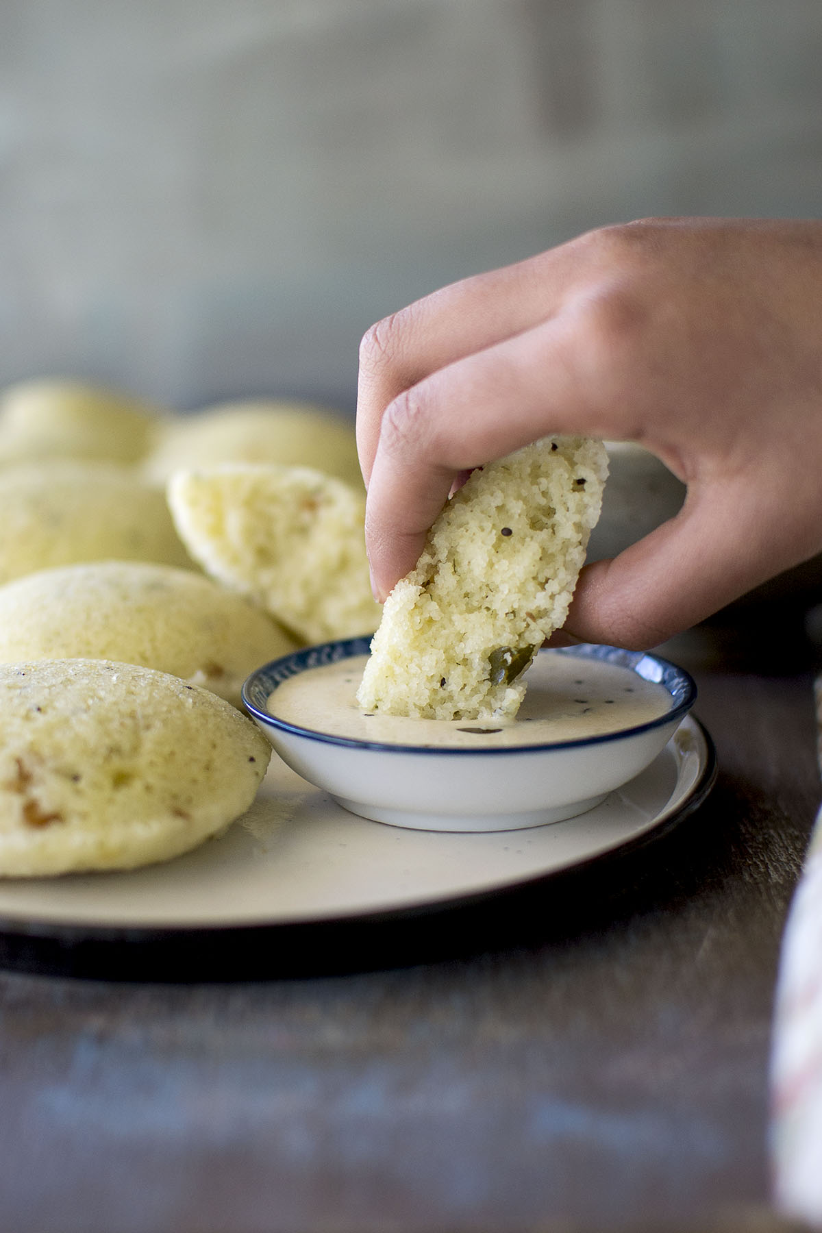 Hand dipping steamed bread in chutney