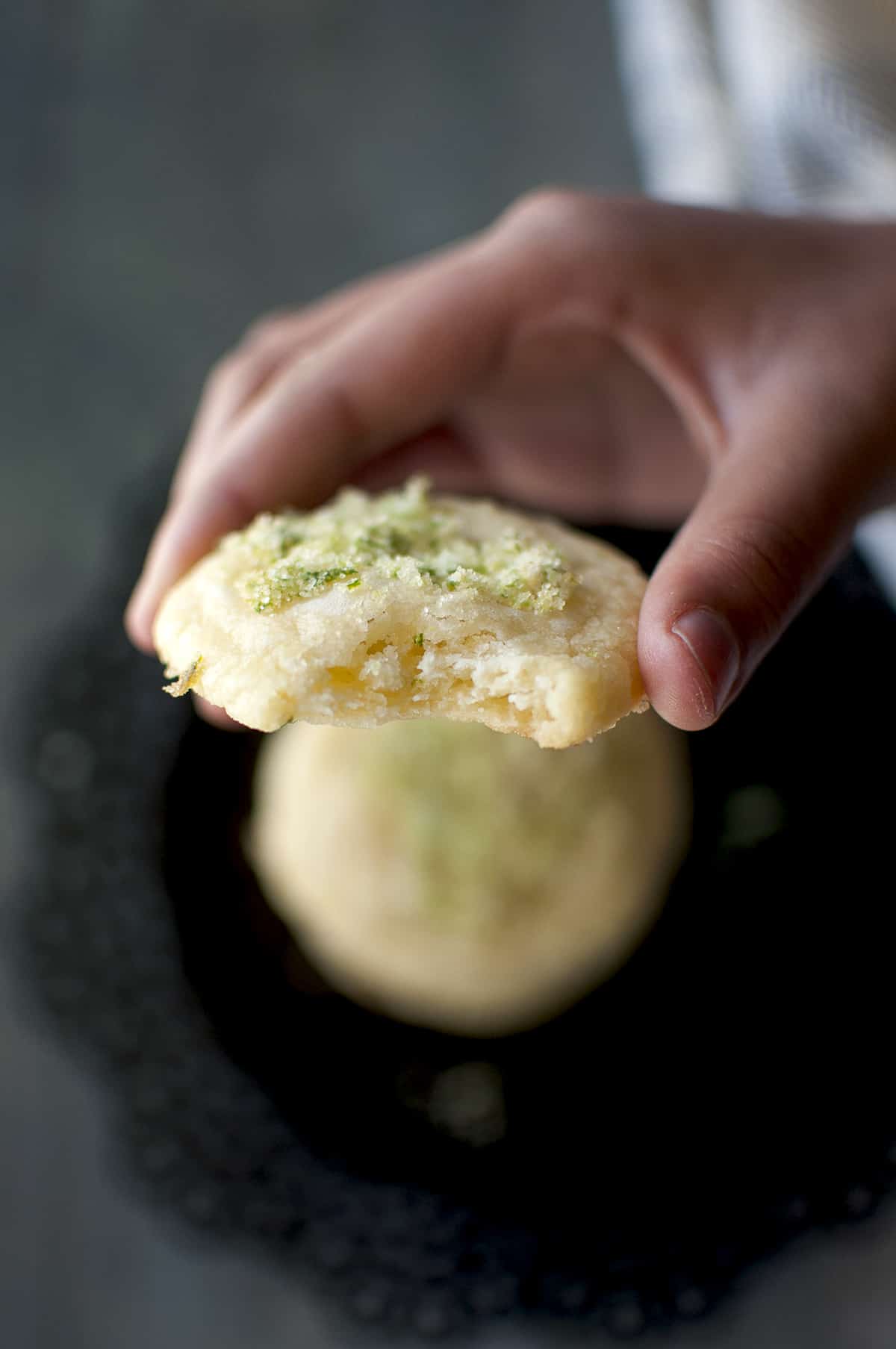 Hand holding a bitten lime cookie