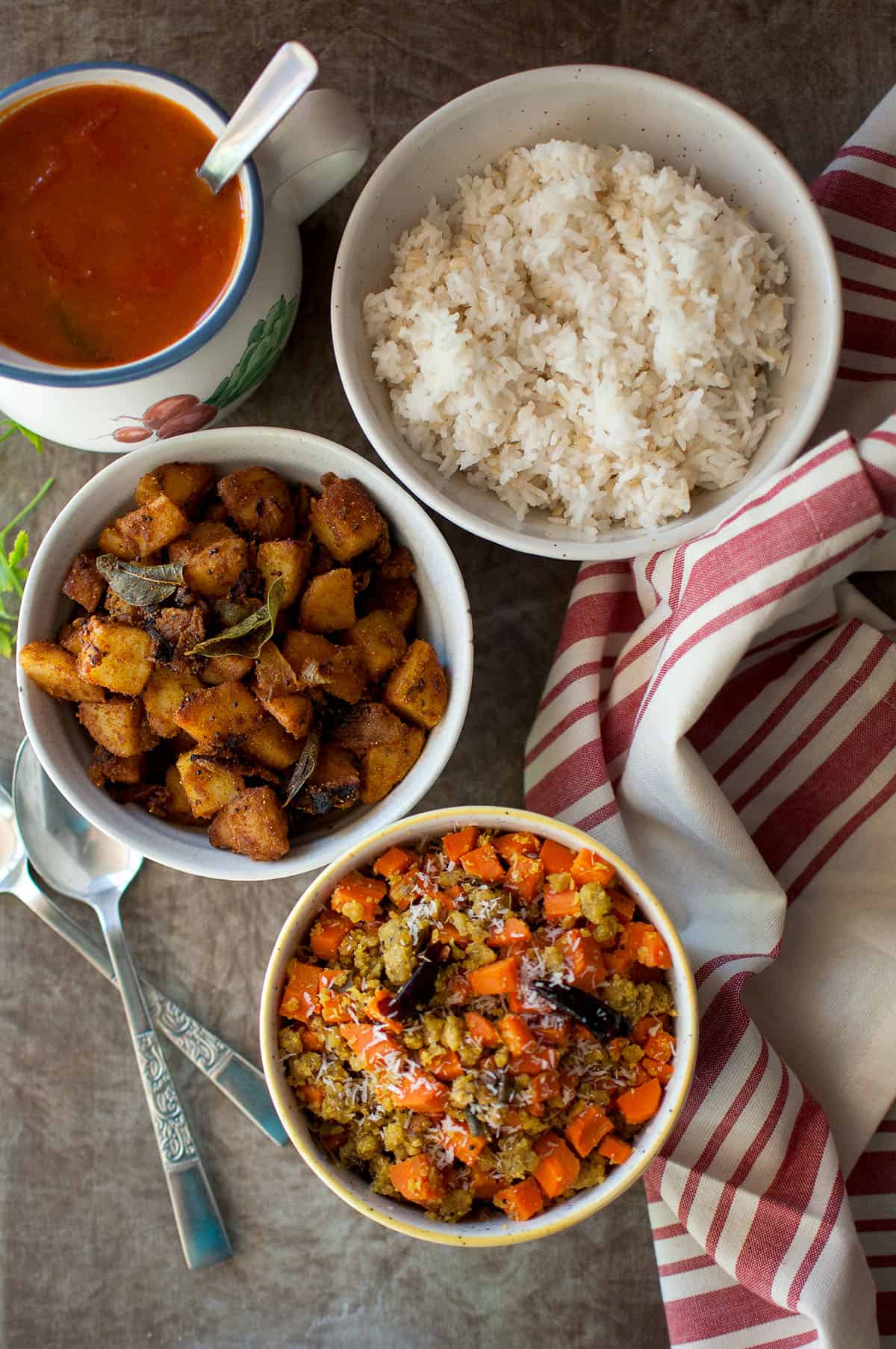 Bowls with carrot paruppu usili, rice and potato fry.