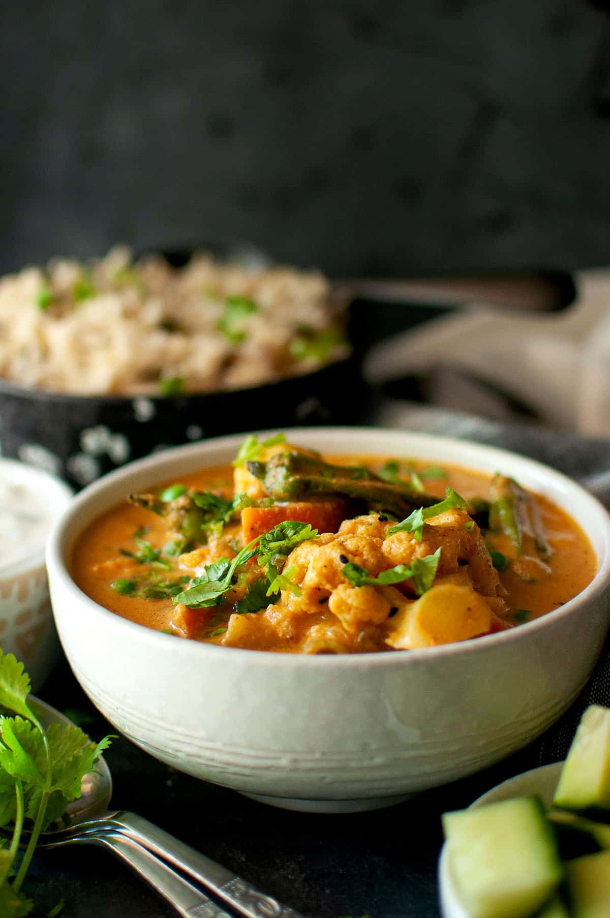 white bowl with salan and a bowl of rice in the background.