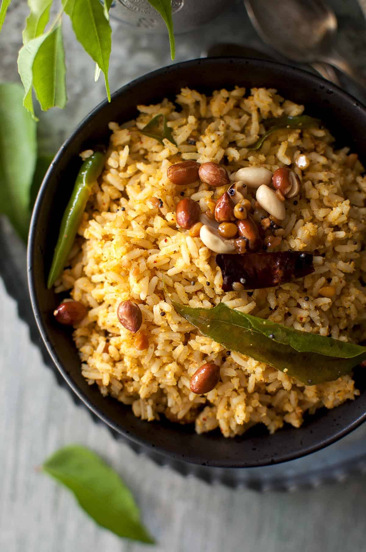 close up view of peanuts topped mango rice in a black bowl