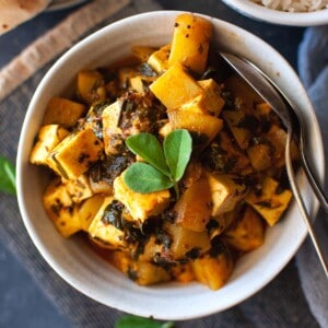 Top view of white bowl with paneer potato curry.