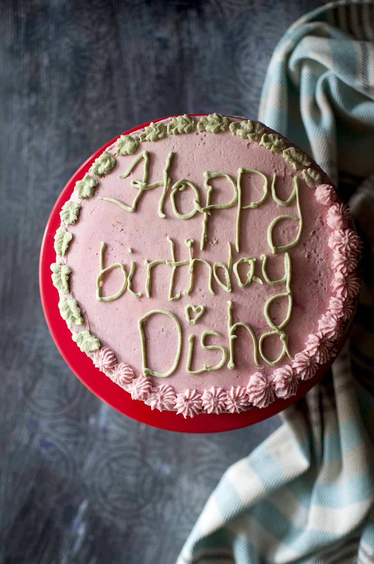 Red cake stand topped with a pink frosted cake