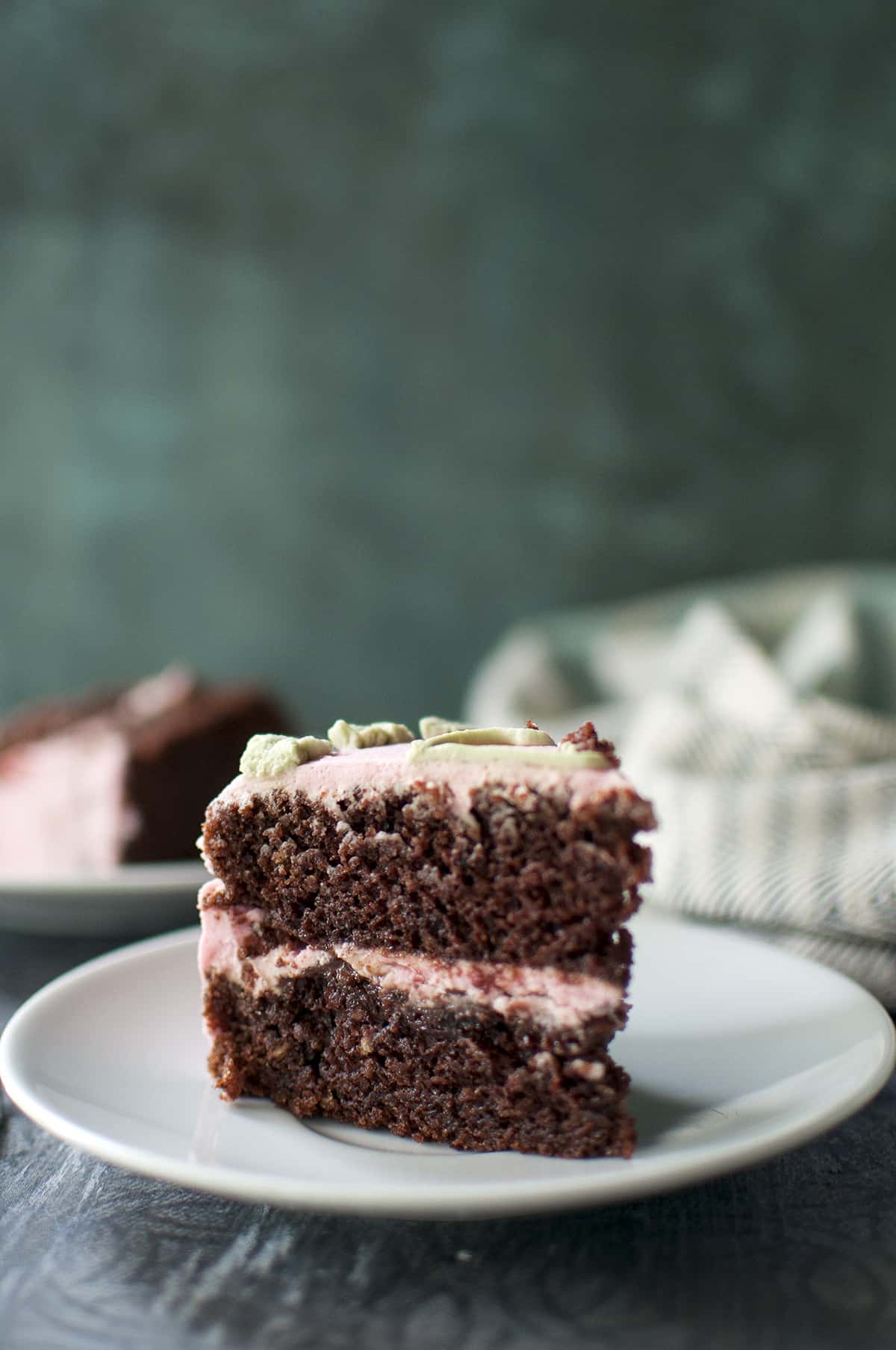 White plate with chocolate cake slice with pink frosting