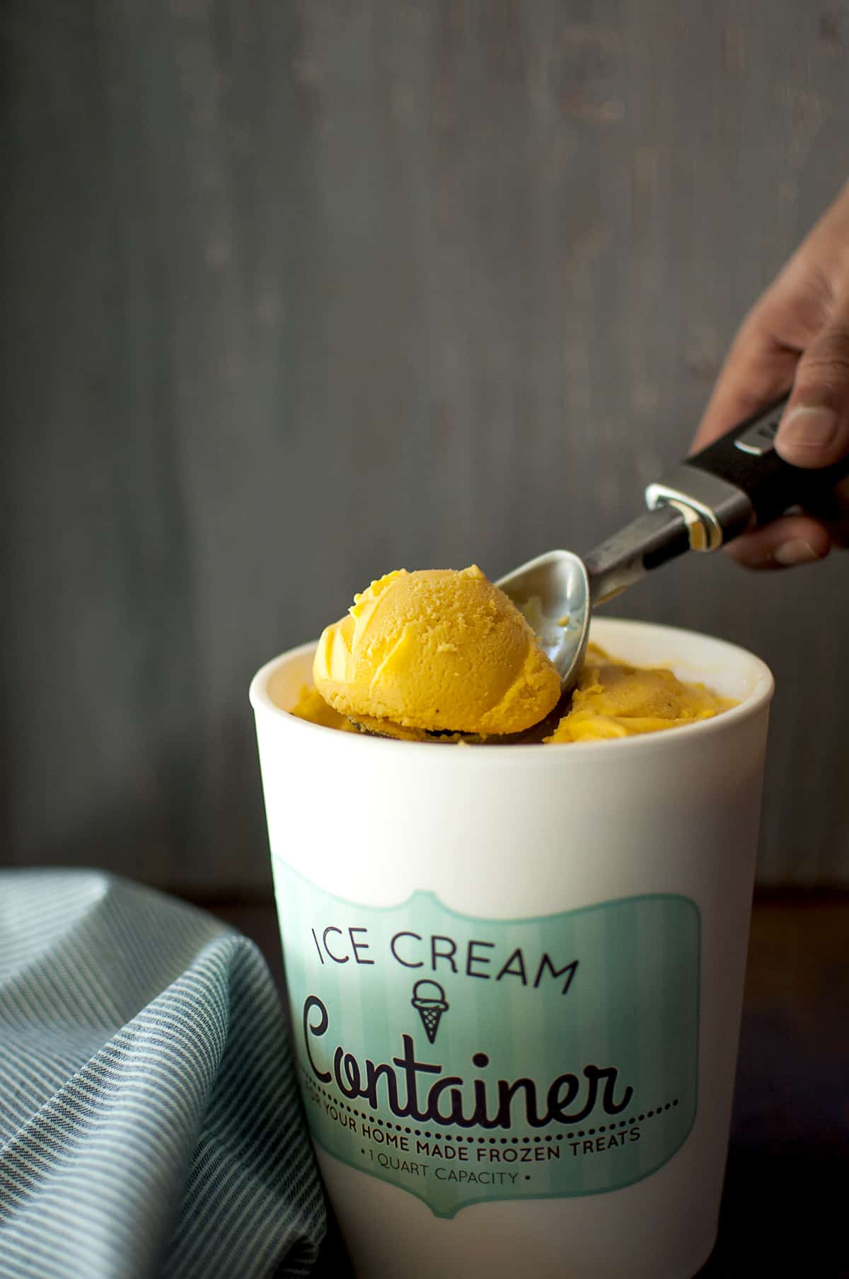 Ice cream container with mango ice cream with a scoop on top