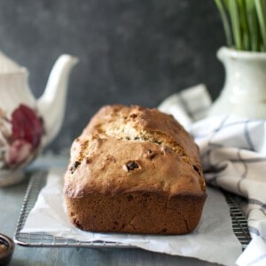 A loaf of banana bread on parchment lined wire rack