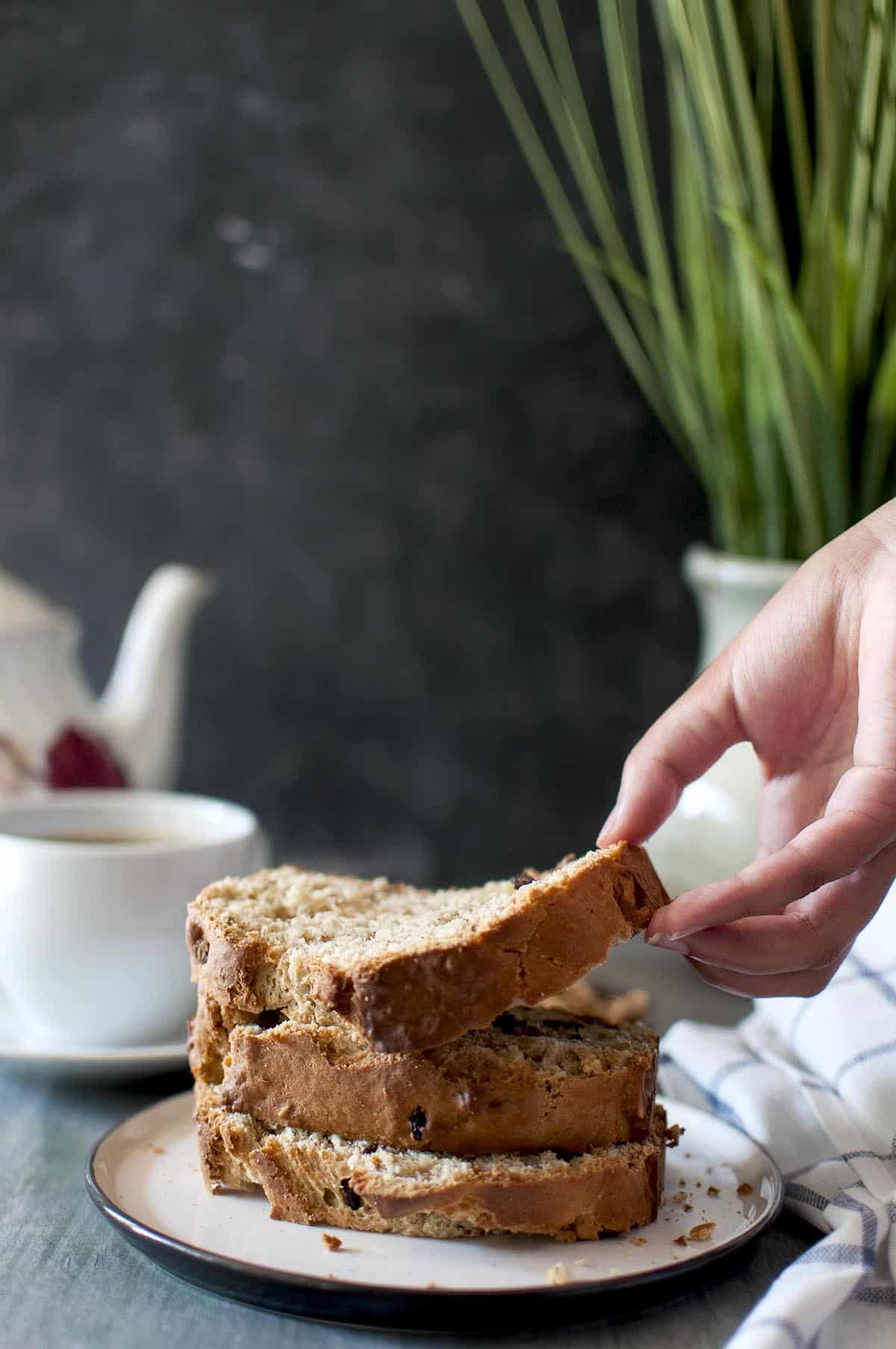 Hand lifting a slice of bread from a white plate