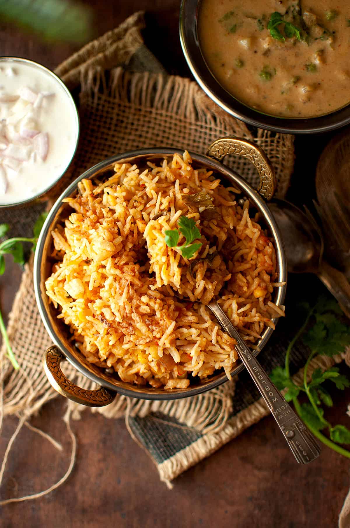 Top view of a bowl with chana dal biryani with a spoon.