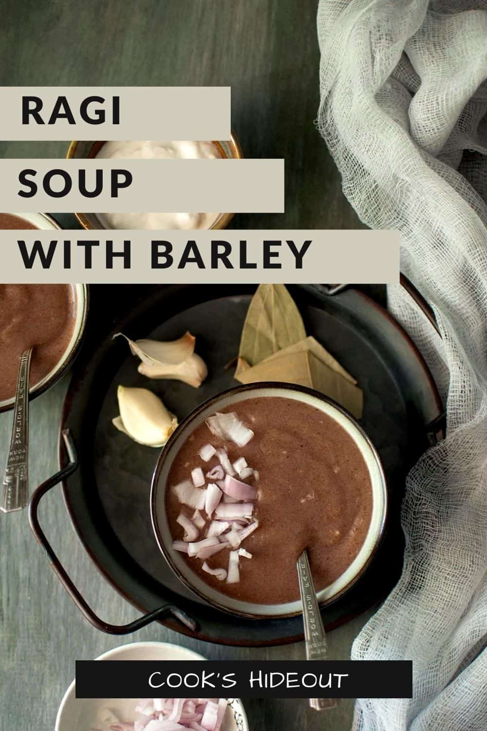 Black tray with a grey bowl of ragi porridge topped with chopped onion and yogurt