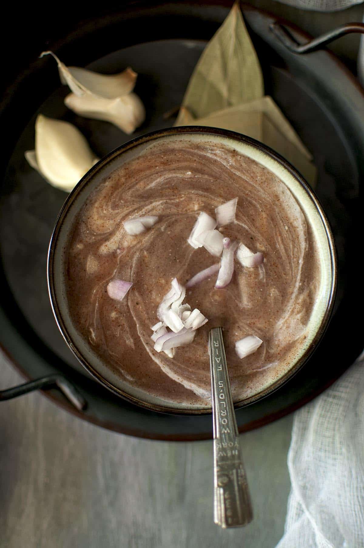 Grey bowl with yogurt and chopped onions wirled ragi soup