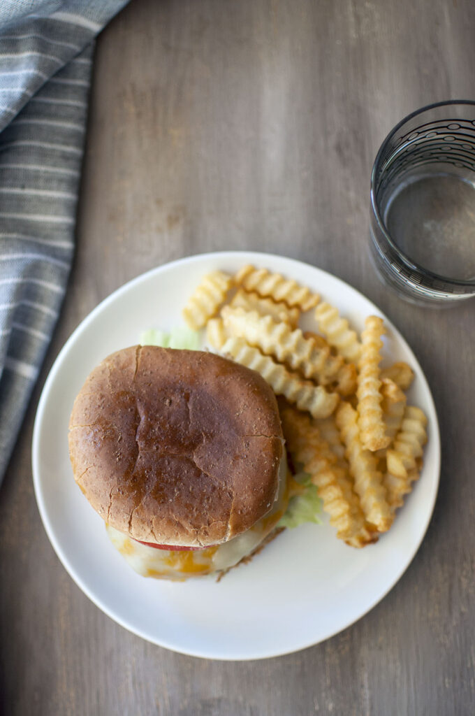 Table with White plate with sandwich, curly fries and glass of water