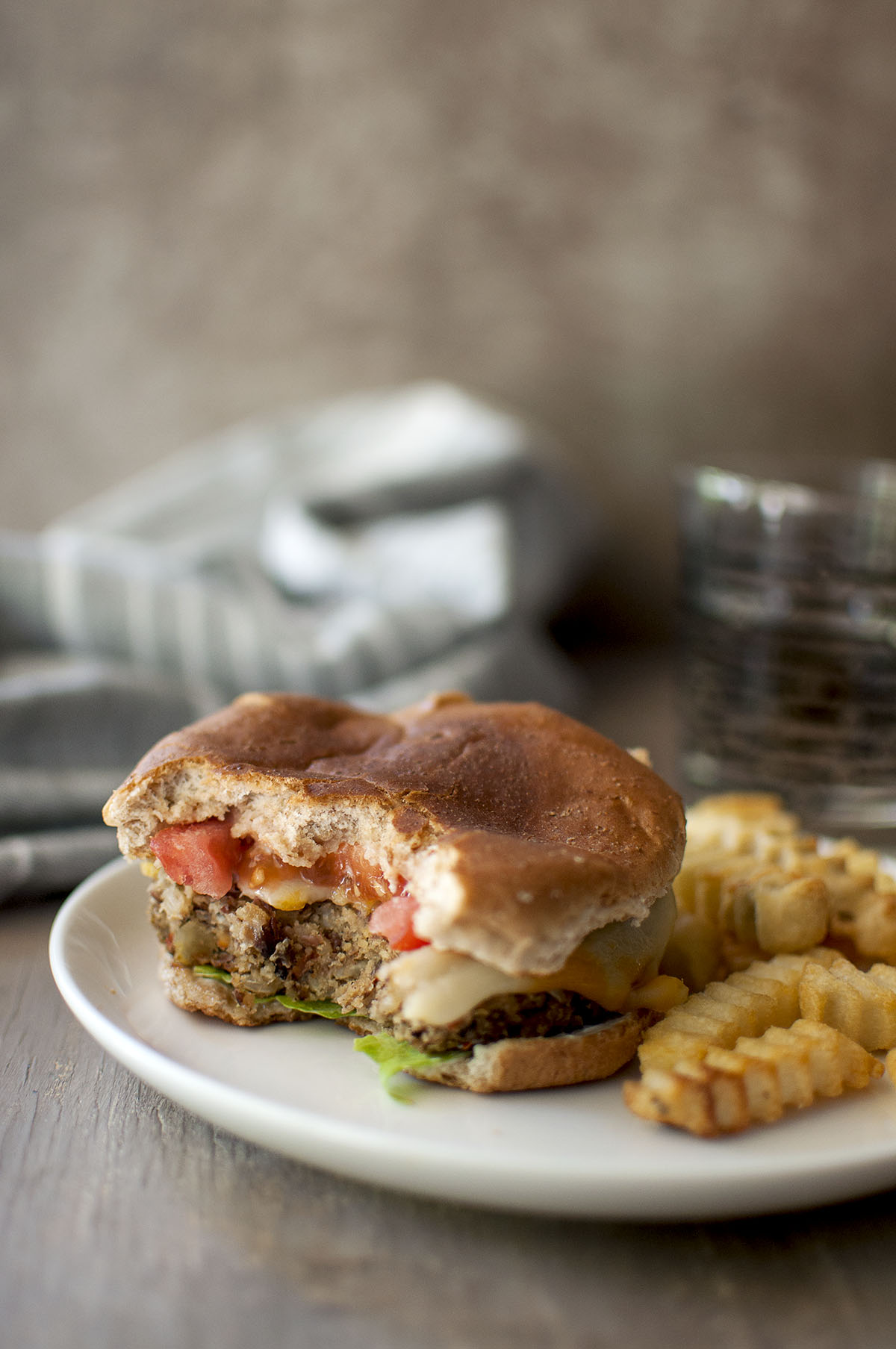 White plate with bitten sandwich and curly fries