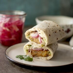 white plate with aloo tikki wrap halves stacked on top of each other