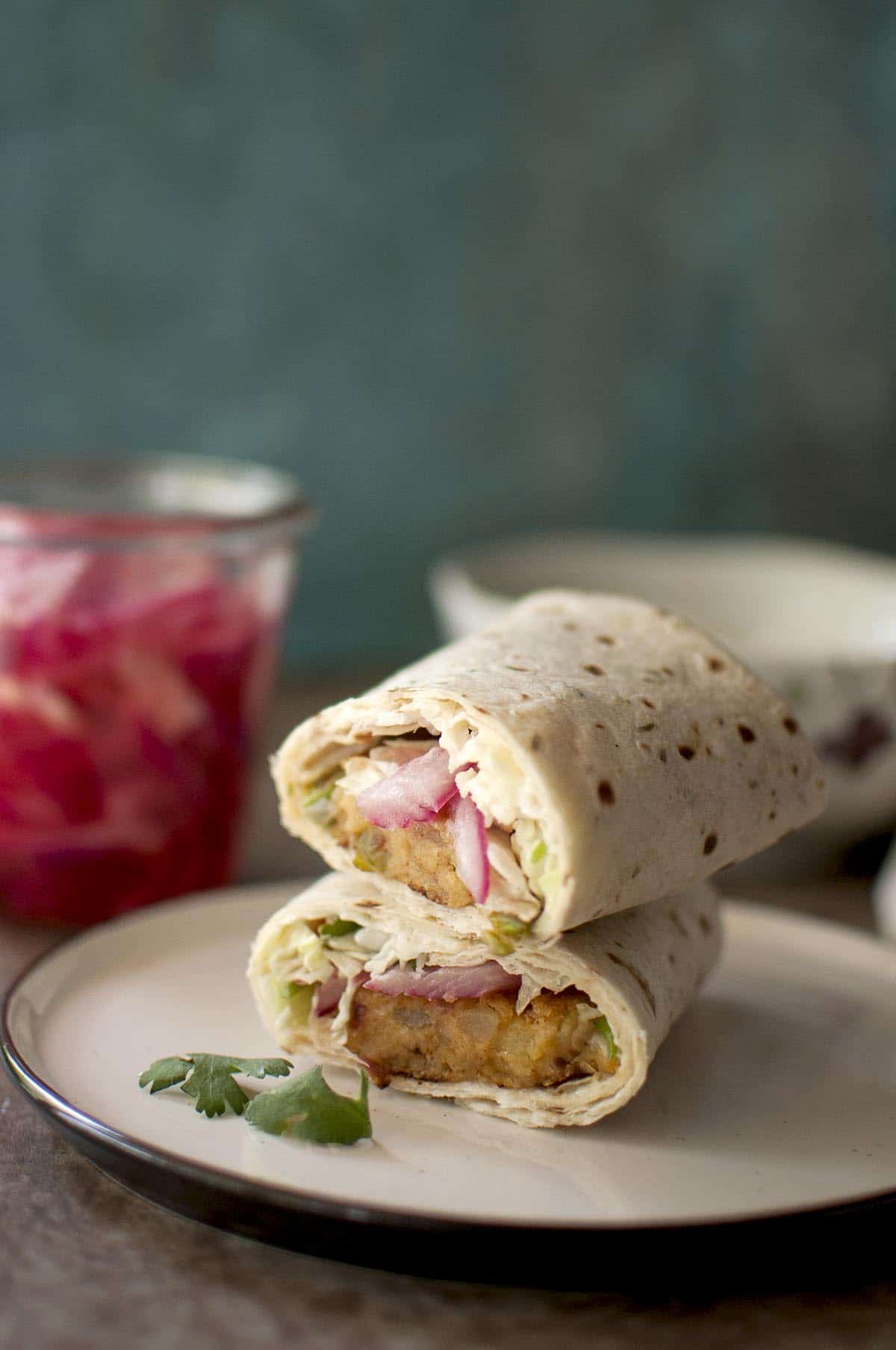 White plate with Aloo tikki wrap halves stacked on top of each other